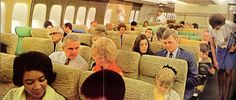 many people are sitting on an airplane and some have their heads turned to the side