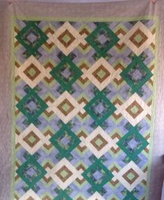 a green and brown quilt hanging on the wall