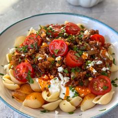 a bowl filled with pasta and tomatoes on top of a table