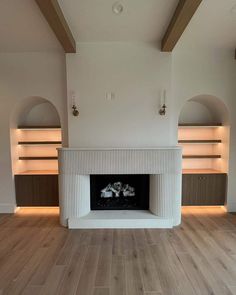 an empty living room with a fireplace and built in bookshelves on the wall