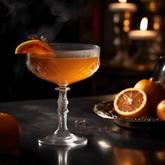 a glass filled with liquid sitting on top of a table next to some oranges