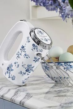 a white and blue flowered pitcher sitting on top of a counter next to eggs