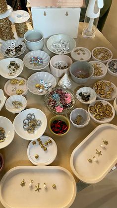 a table topped with lots of white plates covered in jewelry