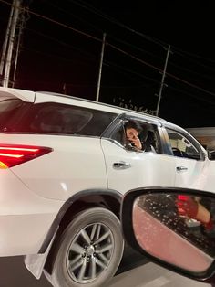 a man is talking on his cell phone in the passenger seat of a white car