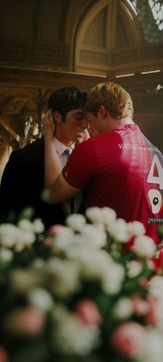 two men embracing each other in front of flowers