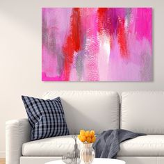 a living room with a white couch and pink painting on the wall above it's coffee table