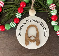 a wooden ornament hanging from a christmas tree with ornaments around it and the words god, jesus, it's your birthday