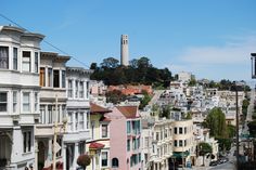 a city street with lots of houses on the side and a tower in the background