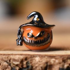 an orange pumpkin with a witches hat on it's head sitting on a piece of wood