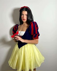 a woman dressed as snow white holding a red flower in her hand and looking at the camera