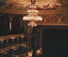 a chandelier hangs from the ceiling in an ornately decorated auditorium