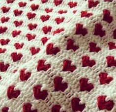 a crocheted blanket with red hearts on it