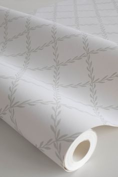 a white wallpaper with leaves on it and a roll of paper next to it