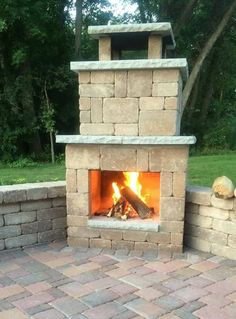 an outdoor fireplace is shown with brick walls and bricks around it, as well as the fire