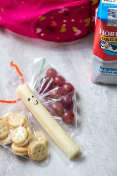 grapes, crackers and cheese are on the table next to a bag with an orange ribbon