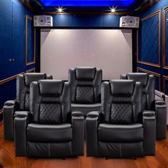 a row of black leather recliner chairs sitting in front of a projector screen