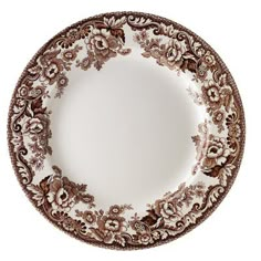 a brown and white plate with flowers on the rim, isolated against a white background