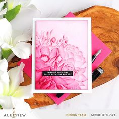 a card with pink flowers and a pen