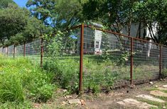 a fence that has some plants growing on top of it in the middle of a field