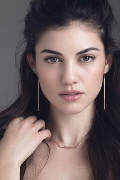 a woman with long brown hair wearing large gold hoop earrings and a choker necklace