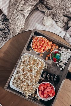 a tray filled with food sitting on top of a wooden table next to a bed