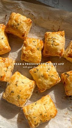 small square pastries sitting on top of a piece of parchment paper with herbs sprinkled on them