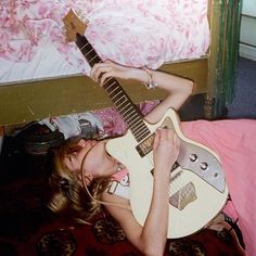 a woman laying on the floor with an electric guitar