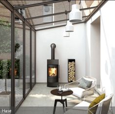 a room with a chair, table and fire place in it that has glass walls