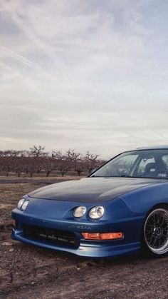 a blue car parked on top of a dirt field