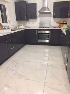 a kitchen with marble flooring and black cabinets in the middle, along with stainless steel appliances