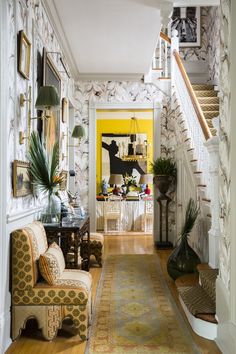 a living room filled with furniture next to a stair case covered in pictures and plants