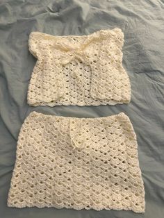 two crocheted baby clothes laying on top of a bed