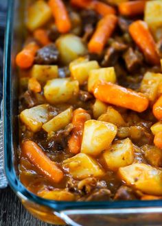 a casserole dish with carrots, potatoes and beef