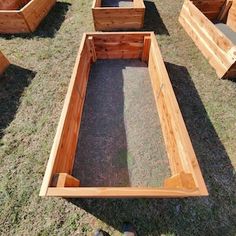 several wooden planters sitting in the grass on top of a field with one empty