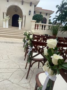 rows of chairs with white roses in them on the side of an outdoor patio area