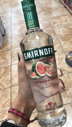 a person holding up a bottle of watermelon in front of a tiled floor