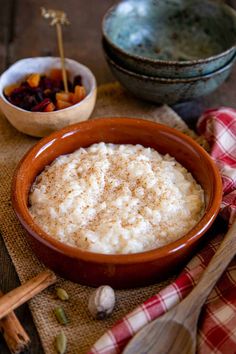 rice in a bowl with spoons next to it on a cloth and wooden utensils