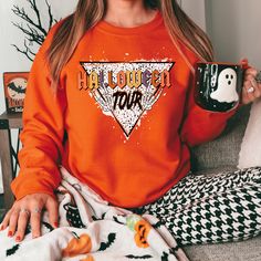 Get ready to embrace the autumn season with our Halloween Tour Sweatshirt, designed to keep you warm and fashionable. Whether you're lounging at home or out for a stroll, this sweatshirt is a versatile addition to your closet. Don't miss the opportunity to stay cozy and chic with our Halloween Tour Sweatshirt! Graphic Print Sweatshirt For Fall Loungewear, Oversized Band Merch Tops For Fall, Trendy Orange Sweatshirt For Fall, Fall Band Merch Long Sleeve Sweater, Fall Band Merch Hoodie With Letter Print, Fall Hoodie With Letter Print Band Merch, Fall Band Merch Tops With Letter Print, Trendy Graphic Print Sweatshirt For Fall, Fall Band Merch Cotton Tops