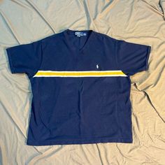 Vintage 90's Polo By Ralph Lauren Collarless Polo V-Neck XXL  Navy shirt with yellow and white stripe on front and back White pony on left breast Excellent Condition  100% Cotton Flat Lay Measurements: Chest 25" Length 26" Sporty Striped V-neck Top, Summer V-neck Top With Contrast Stripes, Striped Cotton V-neck T-shirt, Retro Striped V-neck Top, Cotton V-neck Tops With Contrast Stripes, Cotton V-neck Top With Contrast Stripes, 90s Striped Short Sleeve Tops, Navy Shirt, Ralph Lauren Polo