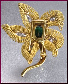 "The captivating flower brooch has a center oval shaped 10.00 ct deep forest green tourmaline. It dates from the 1960's. It is surrounded by 4 gold coiled leaves encrusted with 1.75 ct of round diamonds in the center of each leaf. It all gracefully blooms out of the golden stem. This is enticing appeal all swathed up into a pin. The pin weighs 45 grams. It measures 2 ½ \" long and 2\" wide at its widest point. P 518S SIX MONTH LAY-AWAY AVAILABLE - PLEASE CONTACT ME TO SET UP A PLAN" Elegant Green Gemstone Brooch, Elegant Green Gemstone Brooches, Elegant Green Flower Brooches, Green Fine Jewelry Brooches For Wedding, Elegant Green Oval Brooches, Green Oval Brooches For Formal Occasions, Brooch Diamond, Brooch Flower, Bouquet Gift