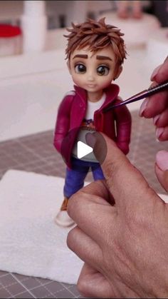 a person is holding a tiny figurine and pointing it at the camera with their finger