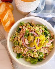 a white bowl filled with salad next to some bread