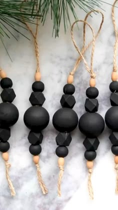 black beads hanging from strings next to pine branch on white marble surface with pine cone decoration