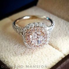 an engagement ring is sitting in a box on top of a carpeted surface, with the diamond center surrounded by two rows of diamonds