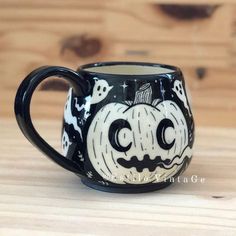 a black and white coffee mug with halloween decorations on the inside is sitting on a wooden surface