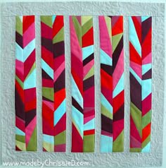 a quilted wall hanging with different colored strips