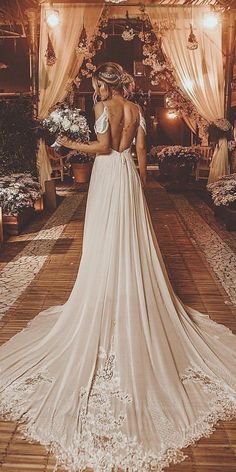 a woman in a wedding dress looking at the back of her gown with flowers on it