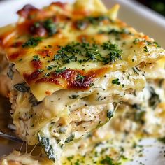 a piece of lasagna with cheese and spinach on it is being held by a fork