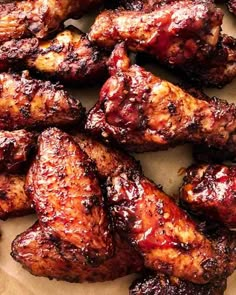 chicken wings covered in bbq sauce sitting on top of a piece of parchment paper