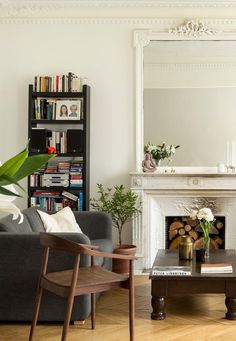 a living room filled with furniture and a fire place in front of a large mirror